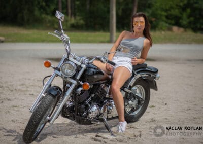 žena sedící na motorce na polní cestě.