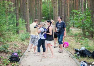 skupina lidí stojících na cestě v lese.