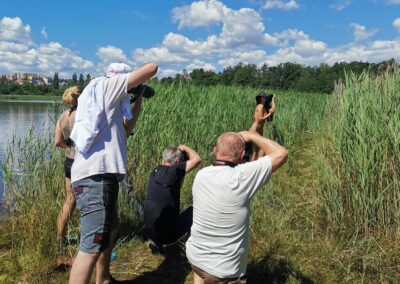 skupina lidí stojících vedle vodní plochy.