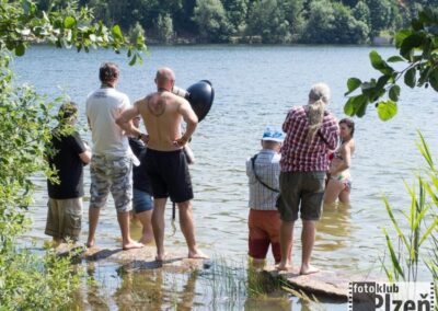 skupina lidí stojících na skále ve vodě.