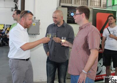 skupina mužů stojících vedle sebe držících sklenky na víno.