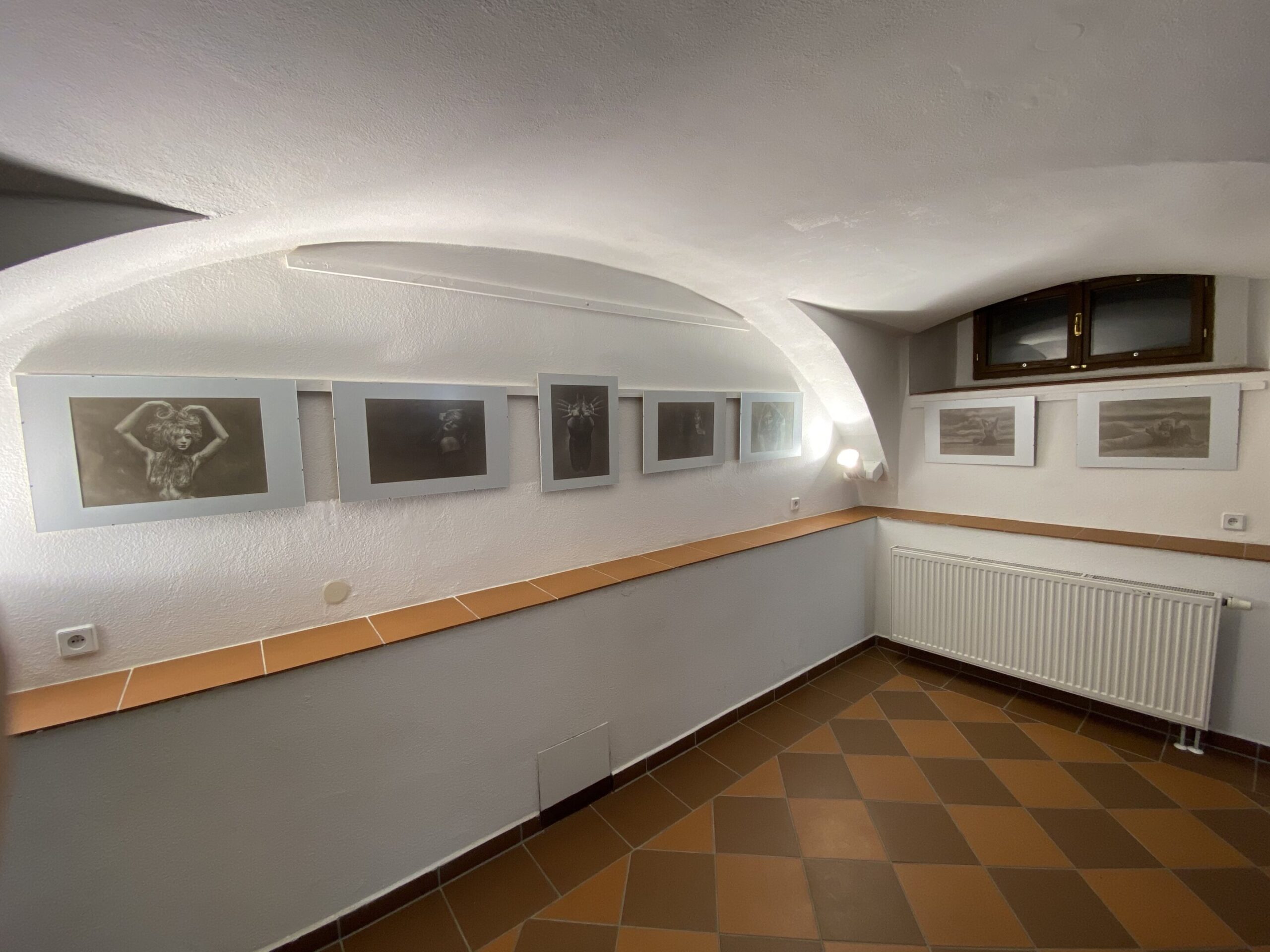 IMG_0297 pokoj s obrázky na zdi a dlážděnou podlahou.