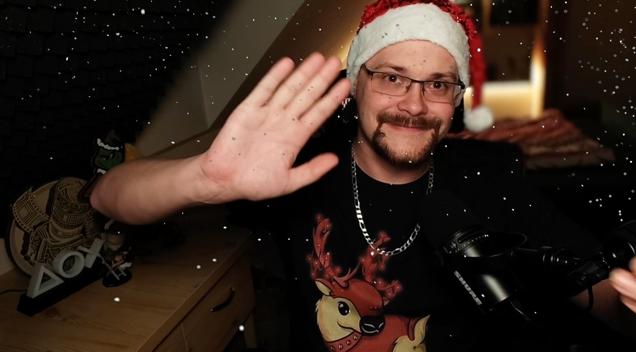 Muž v santa klobouku mává do kamery.